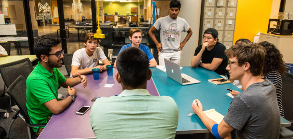 A group of students sit around a lab table