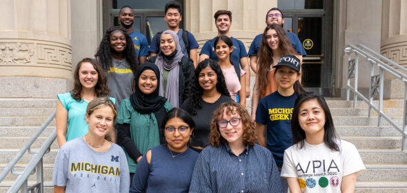 A group of students pose for a photo on the steps of a U-M building