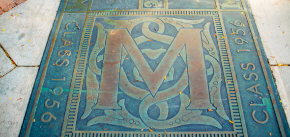 An ornate block M plaque in the sidewalk from the Class of 1956