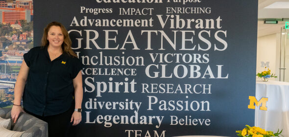 A person stands in front of a large word cloud mural