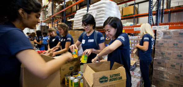 A diverse group of volunteers fill boxes with non-perishable food supplies