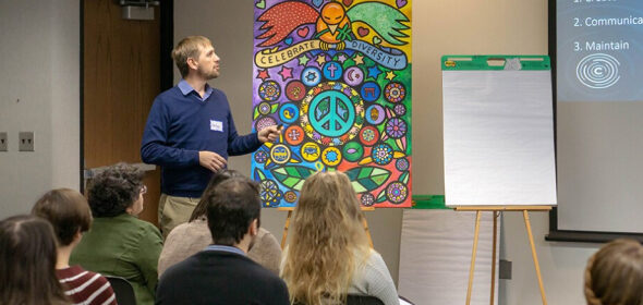 A person gives a presentation in front of a colorful mural