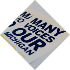 A set of stickers reading "Many Voices Our Michigan"